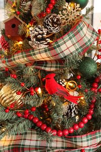 A traditional red and green Christmas tree with plaid ribbon, red beaded garland, red berries, pine cones and beautiful mercury glass ornaments.