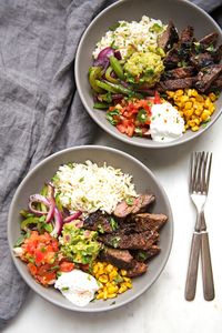 Homemade steak fajita bowls with garlic lime rice. These fajita bowls taste even better than the ones at Chipotle! The secret is the homemade marinade for the steak... it is to DIE for! #steakfajita #steakfajitabowls #fajitabowls #bowls | littlespicejar.com