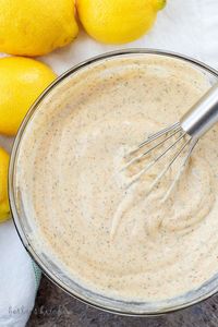 Ariel view of mixed fish taco sauce in a bowl with a whisk beside fresh lemons.