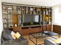 Modern family room | Walnut wood, lacquered mustard yellow and grey bookcase / entertainment center with sliding ladder. Main focus was to display comic collection and double as  storage space.  | Mexico City #HuacalEstudio #Bookcase #Comics #WalnutWood #Ladder