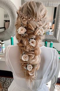 Boho hairstyles are hugely popular for weddings and this dreamy cascading updo makes it clear why—this loose fishtail braid with floral accessories looks like something out of a fairy tale. @wb_upstyles