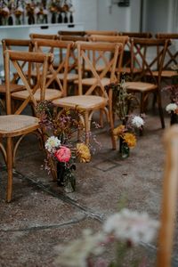 Small floral arrangements in bright colours beside wooden chairs lining the aisle | flowers | aisle decor | wedding aisle inspiration | Mark Horton Photos