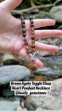 Stunning brown striped agate beaded necklace, featuring a chic front toggle clasp closure and a beautiful agate heart pendant in silver tone. #brownagate #agatejewelry #heartpendant #gemstonenecklace #lovenecklace #heartchoker #brownnecklace #giftformom #giftforwife #toggleclasp #brownstonenecklace #beadednecklace