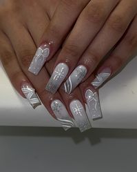 This frosty white manicure with silver details features snowflakes, bows, and delicate line art. The icy tones and intricate patterns evoke a winter wonderland aesthetic. It’s a perfect choice for a magical and chic winter look.