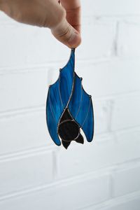 Stained glass suncatcher of a blue bat is a perfect item of decor on the eve of Halloween. This window hanging will make your home look really horror! #windowdecor  #falldecorideas #halloweendecorations #stainedglassart  #stainedglasssuncatcher #stainedglasswindow #stainedglassdecor  #horrorart  #Halloween2020 #handmade #homedecorideas #giftideas #homeaccents #stainedglasscraft #suncatchers