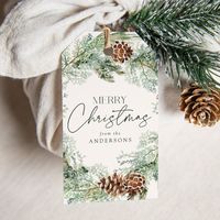 AD: Elegant and rustic holiday gift tags featuring a watercolor wreath of pinecones, pine boughs, and lush greenery with a light cream background. "Merry Christmas" is displayed in a dark green script with your name shown below. The back of the pinecone gift tag displays a dark green background. Designed by Late Bloom Paperie for Zazzle.