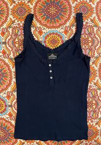 This Lace Trim Knit Cami will level up your wardrobe! A sweet update on the classic rib knit tank, this navy blue top features a crochet lace trim plus three button detail at the chest, giving you a chic yet updated look. Perfect for layering! 100% Cotton