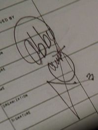 Abby Sciuto's signature. It looks like a skull and crossbones. The two b's are the eyes, the tiny "Sciuto" are the teeth, and the triangle flourish are the bones. If one looks closely, they can see how she did it. From S02E21 "Hometown Hero."