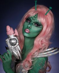 This stunning alien makeup look is sure to turn heads. The green face paint paired with a bright pink wig creates a striking contrast that’s both otherworldly and captivating. The intricate designs on the forehead add a cool sci-fi element, making this look truly unique.   Photo credit by: @marioncameleon