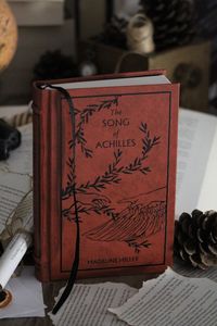 Custom brown leather rebound edition of The Song of Achilles by Madeline Miller. Black details on the cover, black endpages and bookmark.