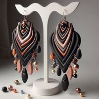 A single pair of large polymer clay earrings, long and dangling. asymmetrical shapes made from clay in black, copper and metallic gold and silver with few colored beads, pearls, and crystals Displayed on a beautiful earring display - Image Creator from Microsoft Designer