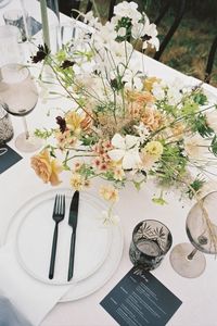 Delicate, airy and organic wedding reception table flowers in shades of white, green, sand and pale peach featuring honey dijon garden roses, white tiger lilies, scabiosa, cherry caramel phlox, nicotiana, chocolate cosmos, white cloud larkspur & seaside grasses.