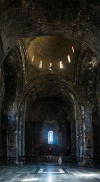 How to get to Tatev from Goris, Armenia - A woman praying in the dark and cool interior of Tatev monastery in Armenia.