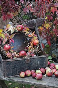 Beautiful fall vignette with a apple wreath, old rake, and a vintage metal box.  So pretty with the red leaves and apples.