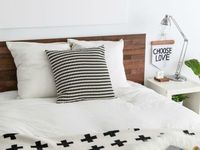 An Ikea Malm bed with white sheets and a black and white patterned bedspread.