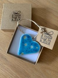 The "a little hug in a box range" from Funky Zebra is a range of small thoughtful gifts for you to send in the post to let someone who you can't be with at the moment know that you are thinking of them. Each of these hearts is handmade in porcelain and glazed with a turquoise/green speckled  glaze.The  little heart is tied with natural twine and measures approx 5cm x 3cm.  P&P cost includes gift as shown in the images.  Please note that as each decoration is handmade each may differ very slightl