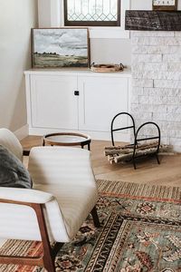 Detailed image showing the combined textures of a natural stone fireplace, white oak floors and a modern striped chair pulled together by Jenny Murphy an interior designer from Northern Colorado.