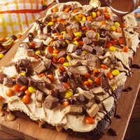 Chocolate peanut butter poke cake is for serious Reese's lovers only. Get the recipe at Delish.com. #delish #easy #recipe #chocolate #peanutbutter #pb #pokecake #cake #dessert #reeses #reesespieces #baking