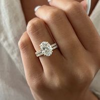 This exquisite engagement ring set showcases a brilliant 3-carat oval lab-grown diamond, complemented by the shimmering beauty of pave-set diamonds. The oval diamond radiates exceptional quality with its brilliant cut facets, while the hidden halo design frames it with smaller accent diamonds, creating a mesmerizing effect. The band itself is adorned with french pave diamonds, adding a sparkling brilliance that enhances the ring's overall allure. Each diamond is securely set in a shared prong se