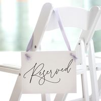 Ritzy Rose's made to order 'Reserved' Wedding Chair Sign elegantly ensures your honored guests' seats are set apart. Customize the ribbon and ink color to seamlessly blend with your wedding theme, adding a sophisticated and personal touch. This sign's graceful calligraphy style print is an exquisite detail for your special day, guiding VIPs to their reserved spot with style. FEATURES & BENEFITS * PRODUCT DETAILS: Paper signs are created from 3 sheets of responsibly sourced linen textured cardstock, elegantly stitched together and finished with hand tied satin ribbon. Packaged in reusable box for safe arrival and storage. * BENEFITS: the design of our ribbon and lightweight yet sturdy materials allow our signs to be carried, worn, or hung from a chair, wall or wagon. We balance the most cur