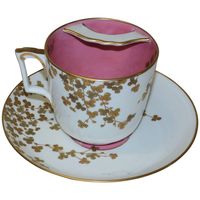 A large Tiffany & Co. moustache cup and plate, in glazed and gilt porcelain, the plate 8 ?" in diameter, and the cup 4 ¾" in diameter. The cup has a bright pink glaze inside, matching the centre of the plate and the back rim of the plate. Both are decorated with raise sprays of three-leaf clovers in gilt. The cup has a transfer printed mark on the underside of Tiffany & Co. and Brownfield's China (partially rubbed), and the plate has a larger and more elaborate transfer and Brownfield's