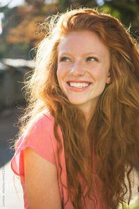 Outdoor portrait of a young ginger woman smiling.