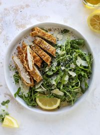 Crispy baked parmesan chicken is super easy to make and so delicious! Served with a simple arugula salad - you will crave this dinner! Baked Parmesan Chicken with Lemon Arugula - Crispy Baked Chicken #bakedparmesan #chicken #salad