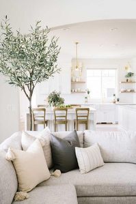 Brown ladder back stools are placed around a white kitchen island lit by a Vendome Small Chandelier.