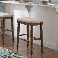 This stool brings extra seating to your kitchen island or home bar. It features a backless saddle seat that lets you slide it underneath tables and countertops to free up floor space when not in use. This stool is upholstered in neutral-toned polyester fabric, and it's foam-filled to provide just the right amount of cushioning as you sit. The curved frame rests on four turned, tapered legs crafted from solid wood. Plus, stretchers on all four sides lend additional stability and support. Hand-cur