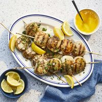 Grilled scallops, cooked on skewers or in a grill basket, are tossed in melted butter with lemon, garlic, and parsley for a succulent seafood treat.