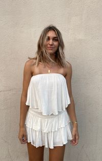 The Monaco White Strapless Romper is a vacay dream! White woven rayon fabric falls from a strapless neckline, with no-slip strips, to a flowy, ruffle overlay bodice with an on-trend smocked overlap back detail. Attached shorts complete the look.