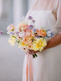 Yellow, peach, lavender, pink, and light blue wedding with a garden style floral arrangement growing up the wall, a cake meadow, and fun unique centerpieces.