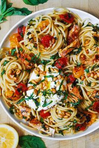 chicken spaghetti with burrata cheese, roasted cherry (or grape) tomatoes, pine nuts on a white plate