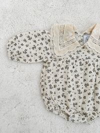 Fall in love with this timeless, elegant romper, crafted from 100% cotton. Featuring an intricate lace collar, floral pattern all over, and convenient buttons at the back and diaper area.