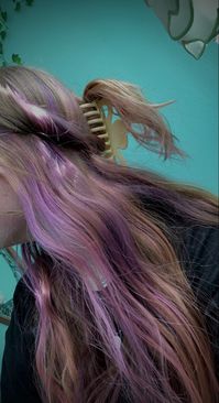 Dirty blond hair with purple hair underneath in a half up half down with the pieces that are held up twisted around the head and held up with a claw clip.