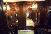 Elegant foyer surrounded with open archways and clad in rich wood paneling that's lighted by candle sconces and gold pendants.