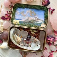 Lovingly handcrafted and adorned with the symbols of the goddess Aphrodite, this portable altar is a perfect companion for witches practicing Hellenic paganism or anyone drawn to the goddess of love, beauty, and the sea. ❤️🌊🐚 ✨WHAT YOU RECIEVE✨ You will receive a miniature altar, which is travel-friendly and can be discreet. Inspired by the goddess Aphrodite and her associations--this altar features a beautiful image of Aphrodite as its focal point and is decorated with moss, seashells, crysta