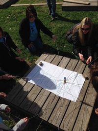 Marker is attached to 8 strings, and the group has to write out a word by working together and only holding onto the last foot foot of each string.