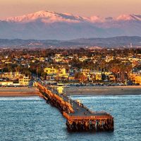 Orange County is home to breathtaking sights. 🧡 Here’s the beautiful, snow-capped San Gabriel Mountains lit up as the sun sets on Seal Beach, CA pier. 😍 Where do you usually go every Sunday? Please share with us your favorite views. Great capture by @jgritchenphoto and @ocregister. #orangecounty #california #SanGabrielMountains #wilsonautomotive #visitcalifornia #socal #southerncalifornia #allthingsorangecounty