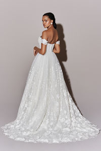 This timeless off-the-shoulder ball gown features a corset bodice with peek a boo embroidered lace along the sweetheart neckline. The skirt is adored with sequined lace appliqués and flows to a chapel length train. 