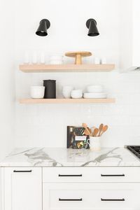 Natural wood open shelving styling in a modern white kitchen with leather stools and a thick marble island | Studio McGee Design Blog