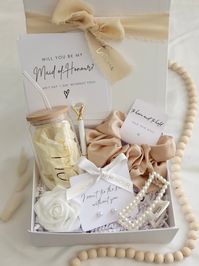 Bridesmaid Proposal Box - a keepsake in itself - includes:  * Magnetic Box with a beautiful personalised ribbon (name on ribbon) * Proposal Card with envelope  * 16oz Glass Tumbler with lid & straw personalised with name * Pearl Earrings S925 Silver with ''I can't tie the knot without you'' card & personalised ribbon * Oversize Scrunchie * Pearl Hair Claw * Diamond Pen * Foam Rose Box information: Magnetic Box, Dimensions (L x W x H): 16cm x 20cm x 8cm Ribbon information: Hand-Tear Chiffon Fabri