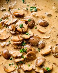 Close up of caramelised mushrooms in creamy sauce sprinkled with fresh finely chopped parsley