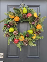 Get the holidays started with this gorgeous faux fruit wreath on your front door to greet guests all season long. This wreath was created with faux life size fruit of red apples, yellow pears, green pears, oranges, plums, gorgeous magnolia, natural pinecones and pine stems. Wreath shown measures 24" in diameter and 7" deep. This wreath along with every wreath you see in our shop is lovingly handcrafted just for you in our shop in St Charles, Il.