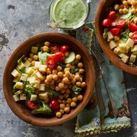 In this cucumber, tomato, Swiss cheese and chickpea salad recipe, a healthy green goddess dressing is made from avocado, buttermilk and herbs. The extra dressing is delicious served with grilled vegetables.