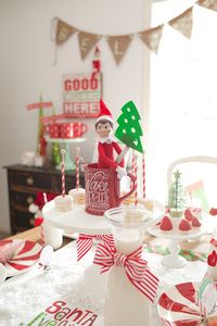 North Pole Breakfast with Santa's Magical Christmas Elf | Welcome Party- Cake Stands with Bananas with Strawberry hats, powdered doughnuts, milk bottles with red stripe ribbons tied around. Christmas plates.