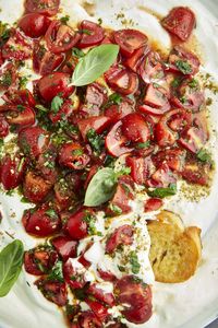 Overhead image of whipped cottage cheese and tomatoes topped with fresh herbs.