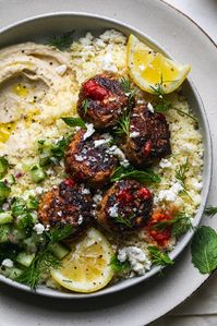 These Harissa Chicken Meatballs are served on a bed of couscous with a refreshing cucumber and herb salad for the best bowl-style meal EVER! We've got a thick layer of hummus, feta cheese, and plenty of fresh herbs, to make these bowls even more flavor-packed and satisfying! This is the kind of dinner you'll find in your rotation constantly, because it's just that simple and that good! #harissa #chicken #meatballs #bowl #mediterranean #healthy #mealprep