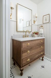 This new guest bathroom in the basement of a row home in Alexandria, Virginia was designed with a mix of British style and vintage American. A custom walnut vanity with turned legs was made from inset cabinetry. Vertical ship lap 3/4 walls provide a subtle contrast of color to the custom patterned hex tile floor.