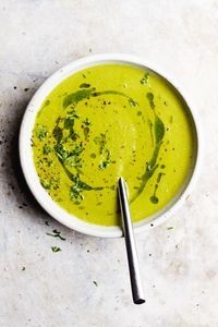 A creamy green tomato soup with caramelized onions, leafy greens, herbed oil and garlic cream. A healthy, gluten-free and vegan green tomato recipe. #greentomatorecipes #greentomatosoup